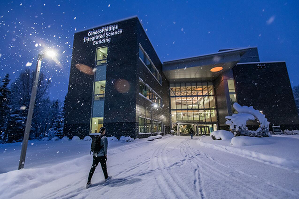 A student walks into a building at UAF during a snowstorm